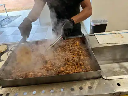 Fresh seasoned meat cooking on the grill for Delicias Daniel Catering